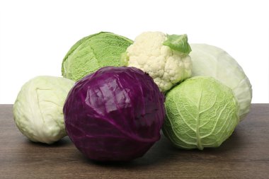 Many different fresh ripe cabbages on wooden table