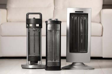 Different modern infrared heater on floor in cozy room