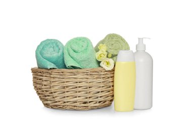 Wicker basket with rolled soft terry towels and flowers on white background