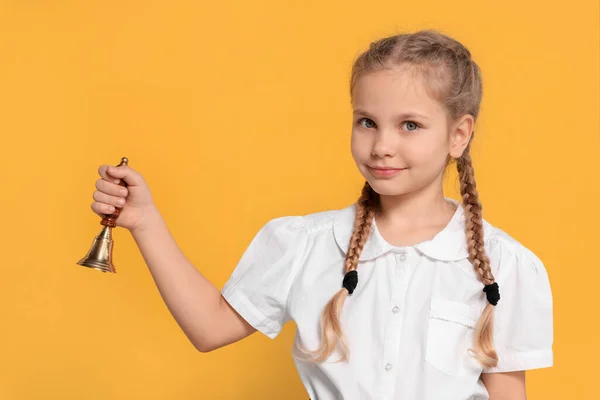 Pupil with school bell on yellow background