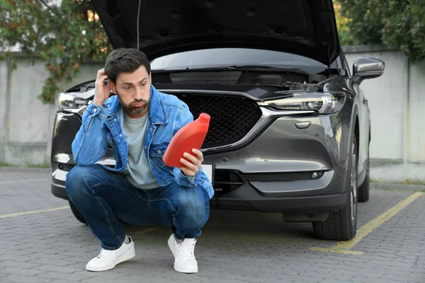 Puzzled Man Holding Red Container Motor Oil Car Outdoors — Stock Fotó
