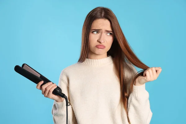 Aufgebrachte Junge Frau Mit Abgeflachtem Bügeleisen Auf Hellblauem Hintergrund Haarschäden — Stockfoto