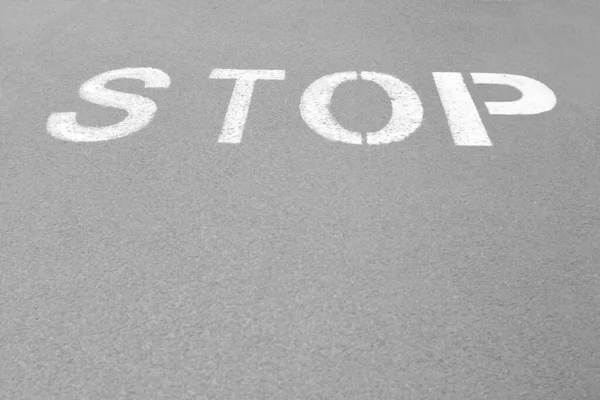 白い看板市内のアスファルト道路上に書かれた停止 — ストック写真
