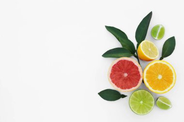 Different citrus fruits and leaves on white background, top view