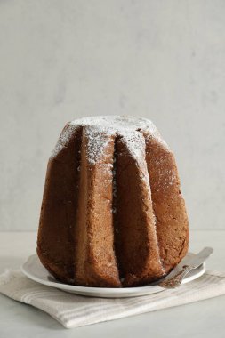 Delicious Pandoro cake decorated with powdered sugar on white table. Traditional Italian pastry