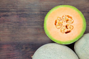 Whole and cut fresh ripe melons on wooden table, flat lay. Space for text