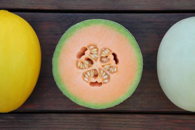 Different types of tasty ripe melons on wooden table, flat lay