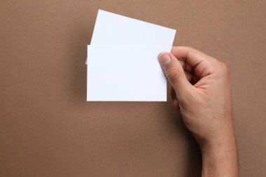 Man holding sheets of paper on brown background, closeup. Mockup for design