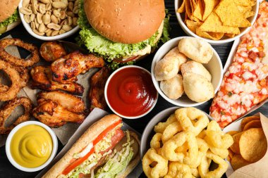Arka plan olarak hamburger, soğan halkaları ve diğer fast food ürünleri.