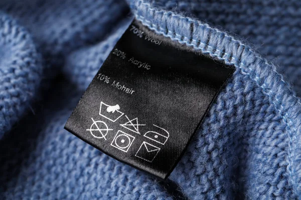 Clothing label on blue knitted garment, closeup