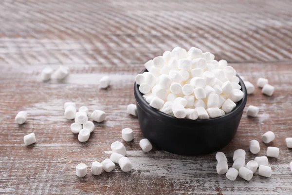Bowl with delicious marshmallows on wooden table