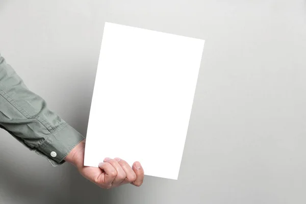 Man Holding Sheet Paper Grey Background Closeup Mockup Design — Stock fotografie