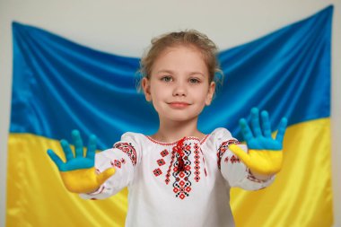 Little girl with painted hands near Ukrainian flag. Love Ukraine concept