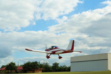 Modern ultralight airplane flying up from field clipart