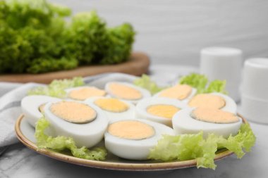 Fresh hard boiled eggs and lettuce on white marble table