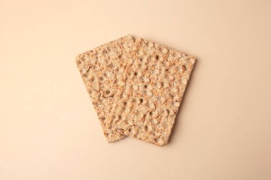 Fresh crunchy crispbreads on beige background, flat lay
