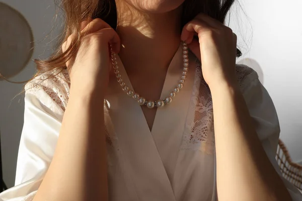 Bride with beautiful pearl necklace indoors, closeup. Wedding day