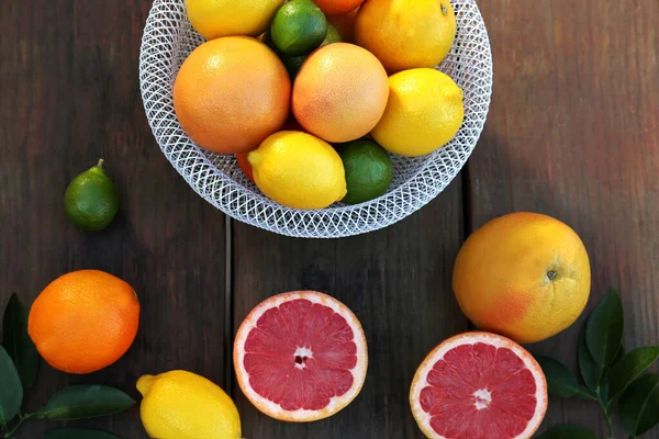 不同的柑橘类水果和叶子放在木制桌子上 平坦地躺着 — 图库照片