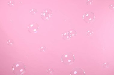 Many beautiful soap bubbles on pink background