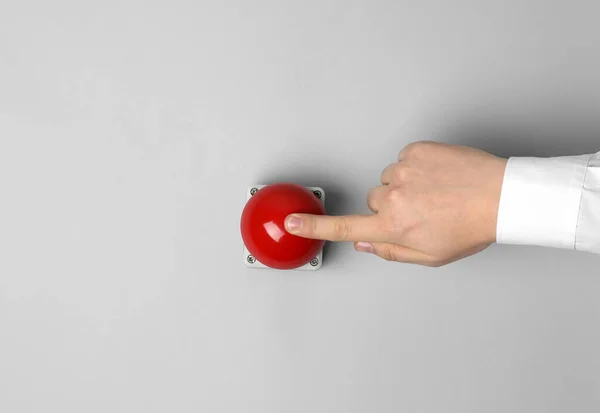 Man pressing red button of nuclear weapon on light gray background, top view with space for text. War concept
