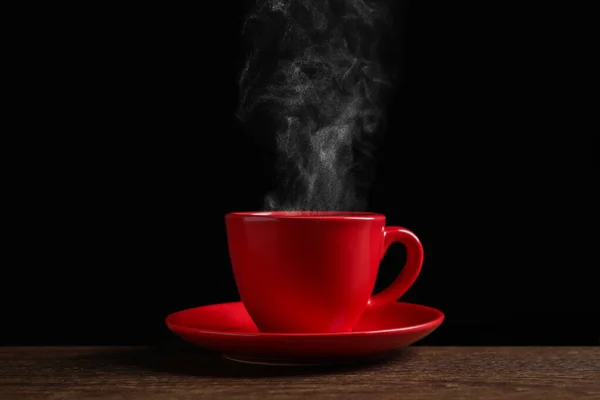 Red Cup Hot Steaming Coffee Wooden Table Black Background — стоковое фото