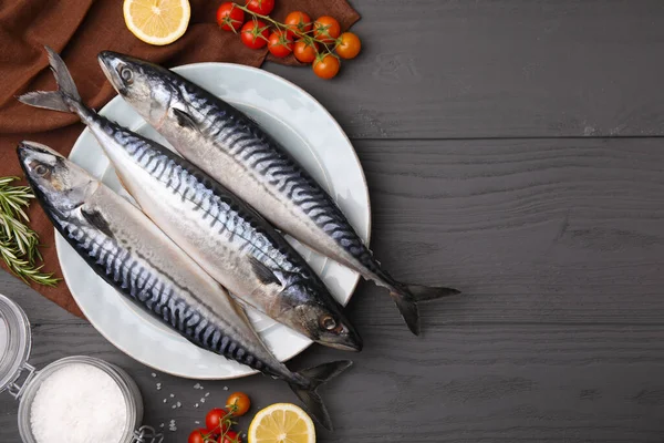 stock image Raw mackerel, tomatoes and lemons on black wooden table, flat lay. Space for text