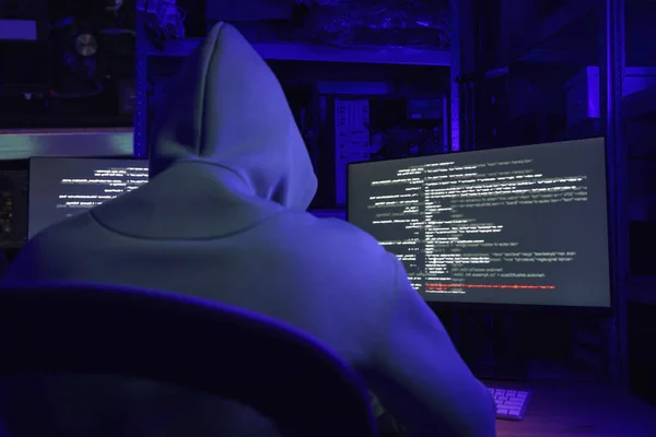 Hacker working with computers in dark room, back view. Cyber attack