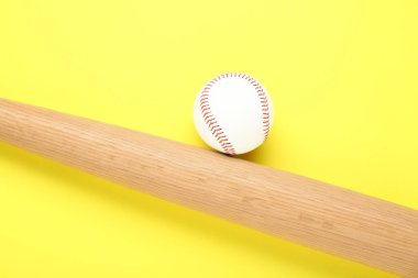 Tahta beyzbol sopası ve top sarı arka planda, düz yatıyordu. Spor malzemeleri.