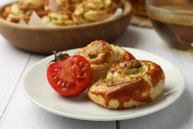 Lezzetli dolgulu taze puf böreği ve beyaz ahşap masada domates, yakın plan.