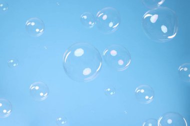 Many beautiful soap bubbles on light blue background. Space for text