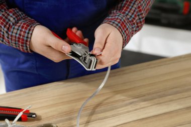 Profesyonel elektrikçi ahşap masada kablo sökme, yakın çekim görüntüsü