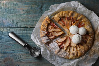 Delicious apple galette with ice cream and pecans on wooden table, flat lay