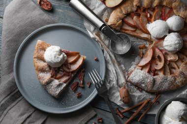 Delicious apple galette with ice cream and pecans on wooden table, flat lay