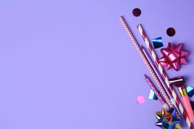 Parti üfleyicisi, renkli konfeti ve mor arka planda diğer şenlikli dekorlar, düz konum. Metin için boşluk