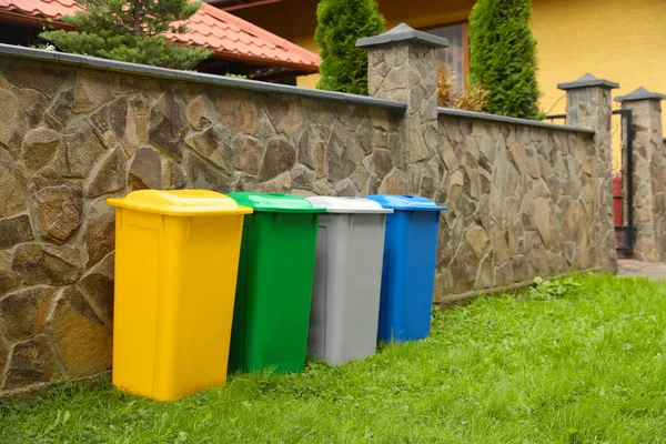 Wiele Kolorowych Koszy Śmieci Pobliżu Kamiennego Ogrodzenia Zewnątrz — Zdjęcie stockowe