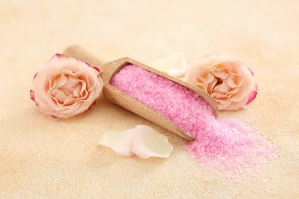 Pink sea salt and beautiful flowers on color textured table