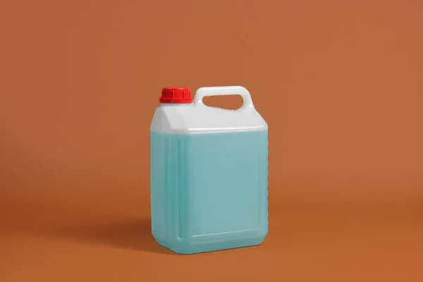Plastic canister with blue liquid on brown background