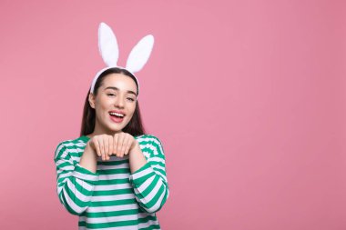 Pembe arka planda tavşan kulaklığı takan mutlu bir kadın. Mesaj için yer var. Paskalya kutlaması