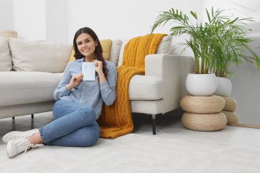 Young woman with greeting card on floor in living room