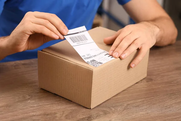 邮局工作人员把条形码贴在室内柜台的包裹上 — 图库照片