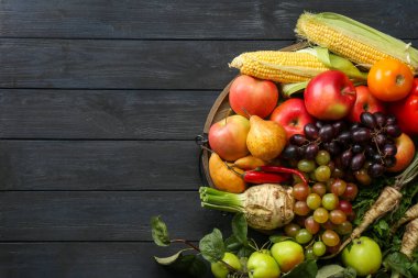 Farklı taze sebzeler ve siyah ahşap masadaki meyveler, yazı için yeri olan üst manzara. Çiftçi hasat ediyor.