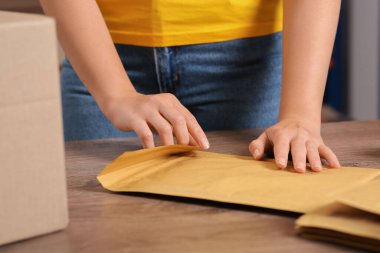 Postane çalışanı, kapalı gişede kağıt poşet yapıştırıyor, yakın plan.