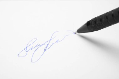 Kalemle beyaz kağıt üzerinde imzalanırken, yakın plan