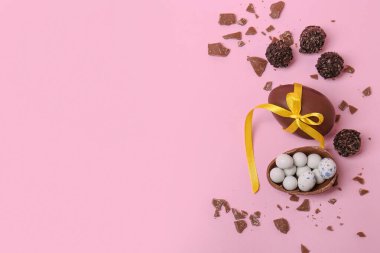 Tatlı çikolatalı yumurtalar ve pembe arka planda şekerler, düz yatak. Metin için boşluk