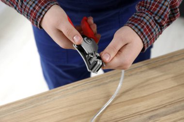Profesyonel elektrikçi ahşap masada kablo sökme, yakın çekim görüntüsü