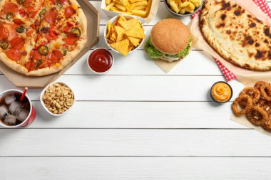 Pizza, soğan halkaları ve beyaz ahşap masa üzerindeki diğer fast food 'lar, yazı için yeri olan düz bir yer.