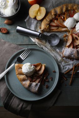 Delicious apple galette with ice cream and pecans on wooden table, flat lay