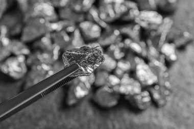 Bulanık arka planda gümüş külçeli cımbızlar, yakın plan. Metin için boşluk