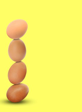 Stacked fresh chicken eggs against light yellow background. Space for text