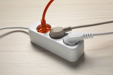 Beyaz ahşap zeminde elektrik prizleri olan uzatma kablosu. Elektrikçi ekipmanı.
